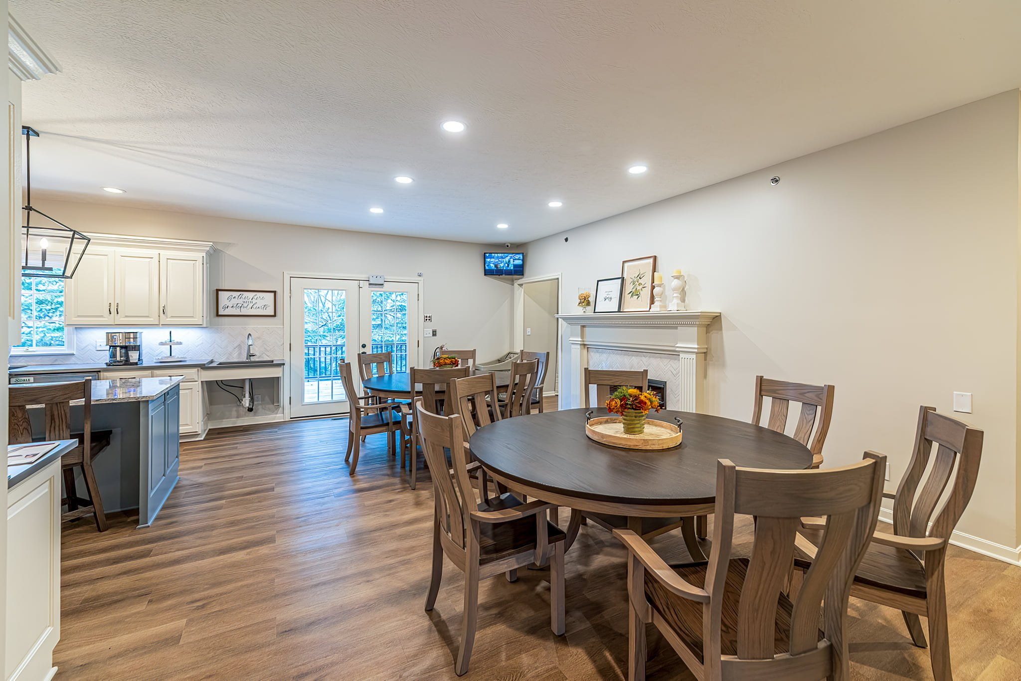 Dining area adjacent to the kitchen featuring an open fireplace, glass doors leading to a balcony, and a scenic view of the woods at Camella Living.